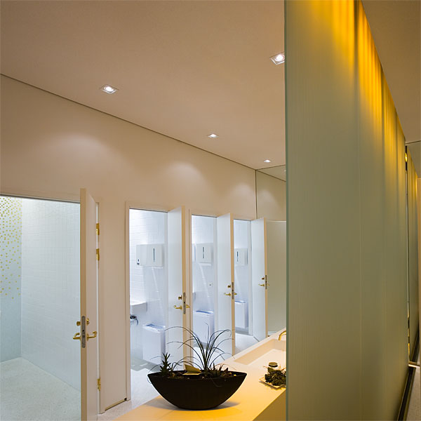 Toaletten med rinnande vatten utmed glasvägg, infärgad med varmvitt släpljus från LED