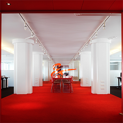 En effektfull lösning: ett 25 meter långt rödmålat rum, som i ena änden avslutas med en helspegel. I taket sitter spotar på en 3 fasskena.