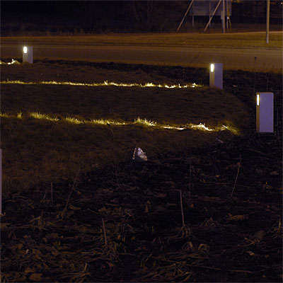 Smala ljuslinjer skär genom gräset och möts på mitten